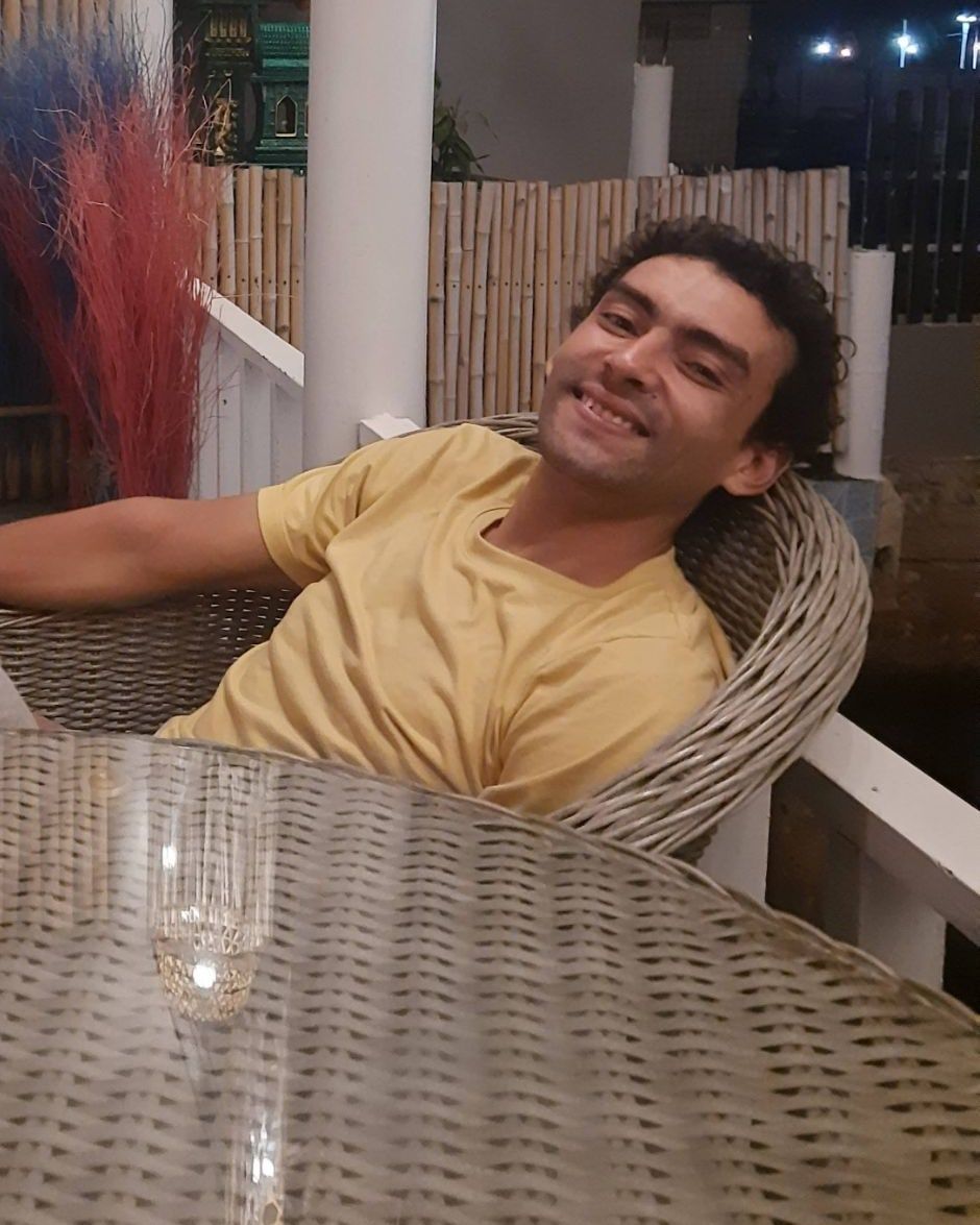 Naoufal relaxing in a wicker chair on a terrace at night.